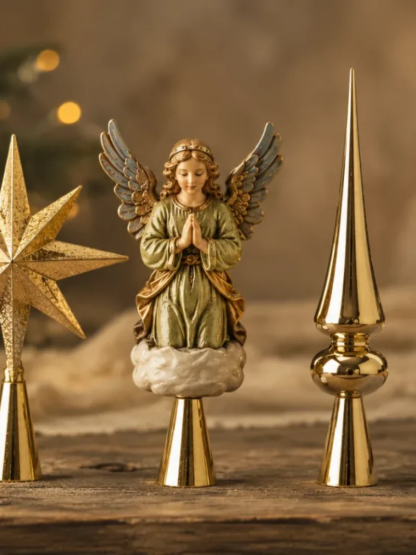 Diversi modelli di puntali per l'albero di Natale disposti su un tavolo in legno, tra cui una stella dorata, una statuetta di angelo e una guglia tradizionale lucida.